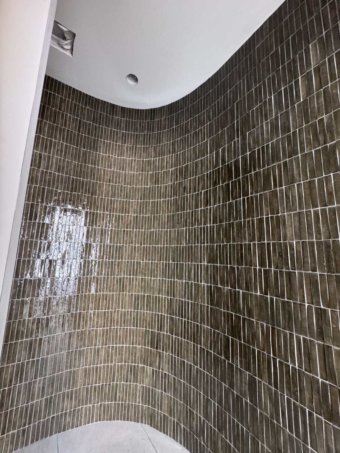 Curved feature wall installed by Reap Surfaceworks with vertically stacked brown glazed tile